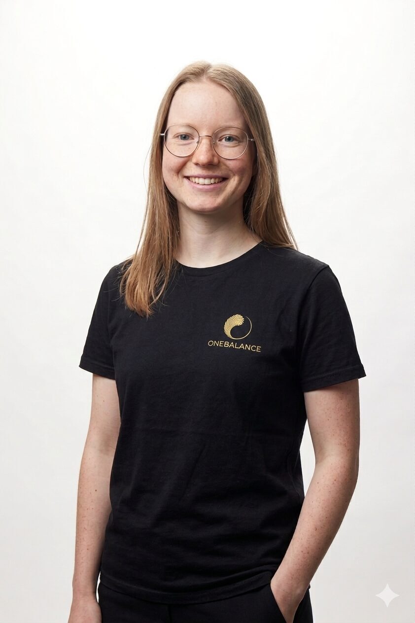 Portrait von ONEBALANCE Physiotherapeutin Isabel Kronenwett im schwarzen ONEBALANCE-Shirt vor hellem Hintergrund